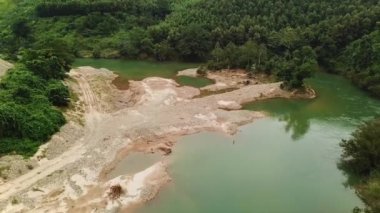 Drone flying near rainforest river surrounded green jungle and mountains. Aerial view of beautiful tropical landscape.