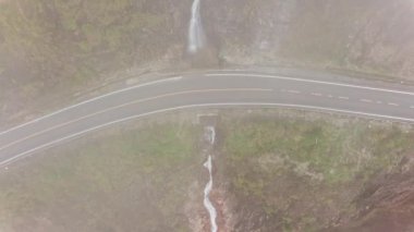 Drone flying near winding mountain road surrounded misty fog rainforest. Aerial view majestic tropical mountains landscape.  