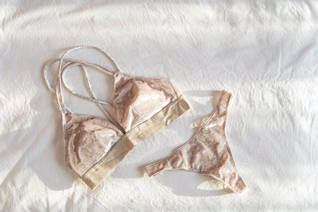 Casual lingerie on white bedsheets. Flat lay with everyday underwear. Beautiful velour bralette and panty.  Shopping and fashion concept.