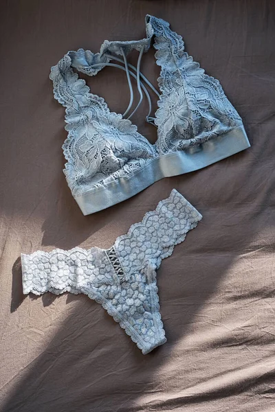 Gri çarşaflara dantelli iç çamaşırı. Romantik iç çamaşırlarıyla yatıyordu. Güzel dantelli sütyen ve külot. Alışveriş ve moda konsepti.