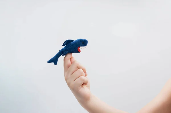 少年は動物の指のおもちゃの図を再生します 子供の手 人形劇の指に置かれたサメの姿 — ストック写真