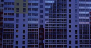 Çağdaş apartmanın, pencerelerin ve balkonların renkli görünüşlü insansız hava aracı görüntüsü. Gece vakti gökyüzü görüntüleri yükselişte..