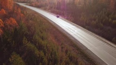 Güneşli sonbahar karayolunda araba sürüşünün havadan görüntüsü. Sonbahar manzarası, çakıl yolu boyunca uçan aracın üzerinde uçan sinematik dron görüntüsü. Yerel seyahat, yol gezisi, kaçış..