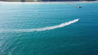 Deniz kıyısında paraşütle atlayan turistler, insansız hava aracı manzarası. Tropik sahilde paraşütle atlayan insanların hava görüntüleri..