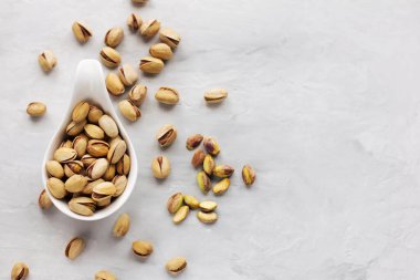 Beyaz bir plaka, gri arka planda kabuklu rav fıstıklı.