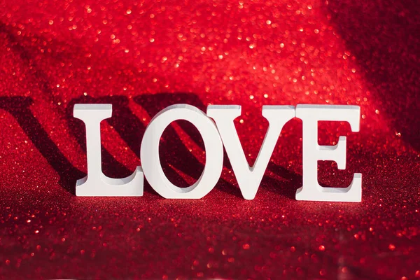 Love という言葉は 赤い輝きの背景に白い文字で作られています バレンタインデー 柔らかい本 — ストック写真