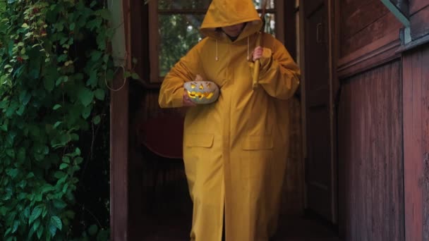Mujer con un hacha, con una calabaza para Halloween en el porche de una casa vieja — Vídeo de stock