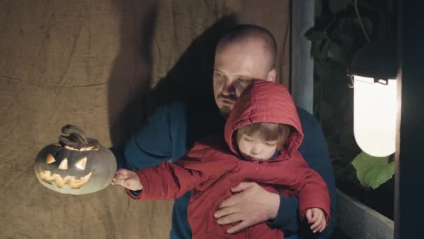 Vater und Tochter sitzen auf Veranda und spielen zu Halloween mit Kürbis — Stockvideo