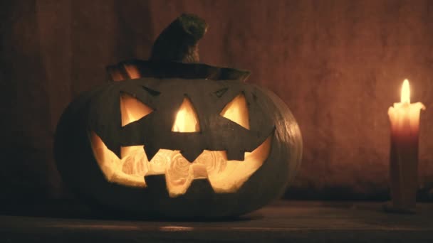 Tökfej Halloweenre ijesztő arccal egy fából készült verandán. — Stock videók