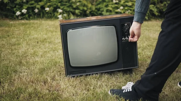 Człowiek włącza stary telewizor retro stojący na trawie Zdjęcie Stockowe