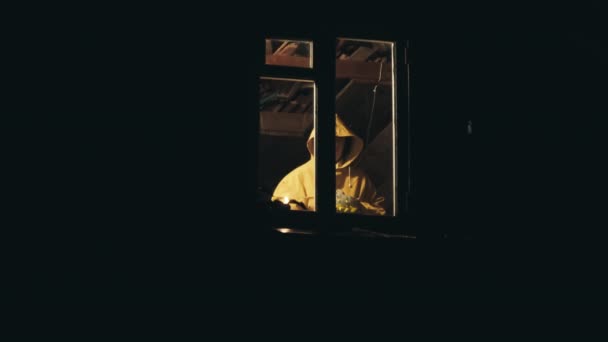 Жінка в плащі у вікні будинку. У руках жінки, гарбуз на Хеллоуїн — стокове відео