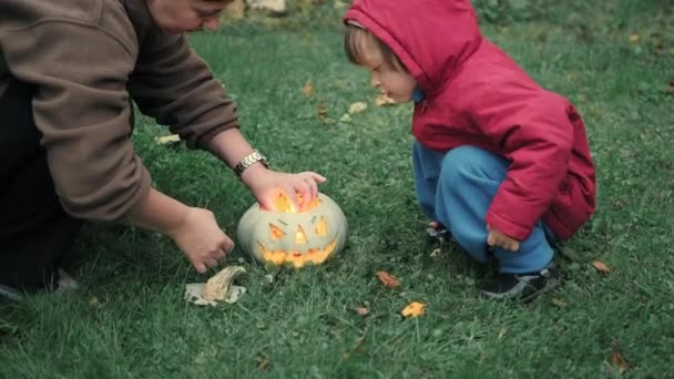 Mamá y una linda niña están encendiendo velas dentro de una calabaza para Halloween — Vídeo de stock