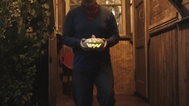 Man In a cowboy hat with a pumpkin for halloween on the porch of an old house — Stock Video