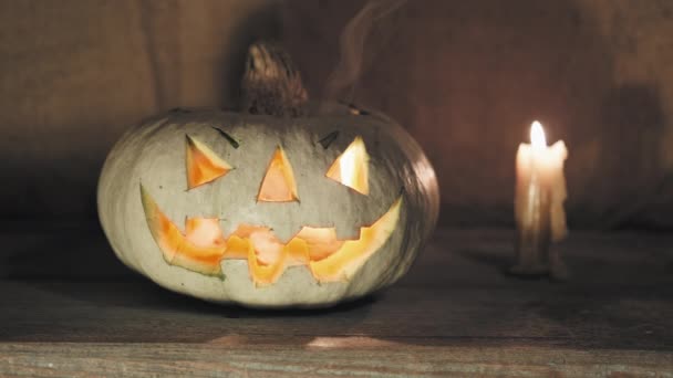 Halloween pompoen met een eng gezicht staat naast een brandende kaars — Stockvideo