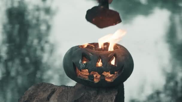 Halloween. Ein Mann setzt eine Mütze auf einen heißen, dampfenden Kürbis mit einem schrecklichen Gesicht — Stockvideo