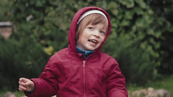 Nettes kleines Mädchen in Kapuzenjacke ist glücklich und macht vor der Kamera Gesichter — Stockvideo