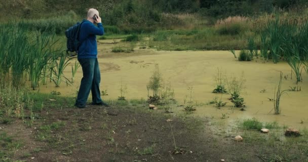 Caminante con mochila y teléfono se acercó al pantano. El hombre no puede caminar por el atolladero — Vídeos de Stock