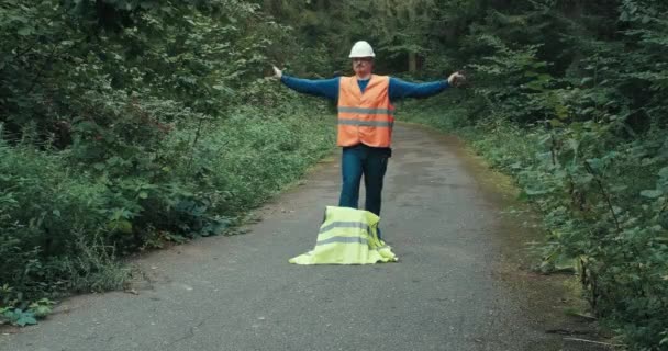 Trabalhador em sinais de vestuário de trabalho com gesto de que a passagem na estrada da floresta está bloqueada — Vídeo de Stock