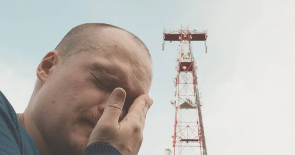 Torre de radio celular 4G y 5G, el hombre tiene un mal dolor de cabeza —  Fotos de Stock