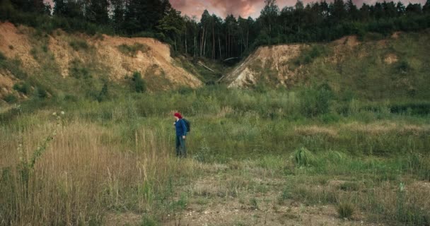 Πεζοπόρος περπατά με ένα σακίδιο σε ένα μεγάλο, αμμώδες λατομείο το ηλιοβασίλεμα — Αρχείο Βίντεο