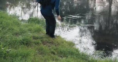 Sırt çantalı bir yürüyüşçü yabancı bir nehirden su içer.