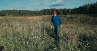 Yürüyüşçü gün batımında büyük, kumlu bir taş ocağında sırt çantasıyla yürüyor.