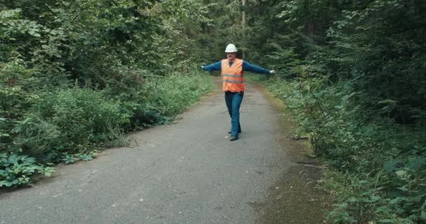 Trabalhador em sinais de vestuário de trabalho com gesto de que a passagem na estrada da floresta está bloqueada — Vídeo de Stock
