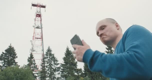 4G és 5G mobiltorony, egy férfi áll mellette telefonnal. — Stock videók