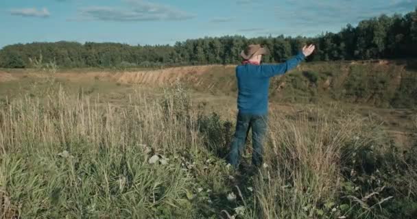 Пешеход в ковбойской шляпе, песчаный карьер на закате. Мужчина разговаривает по телефону — стоковое видео