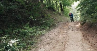 Kırmızı bandanalı bir adam yaz ormanının ortasında dik bir yamaçta koşar.