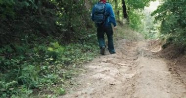 Elinde bıçakla kovboy şapkası takan avcı dik yamaçta yürüyor.