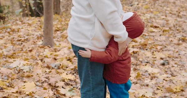 Bonito, pequeno bebê abraça a mãe no parque de outono. Tempo frio — Fotografia de Stock