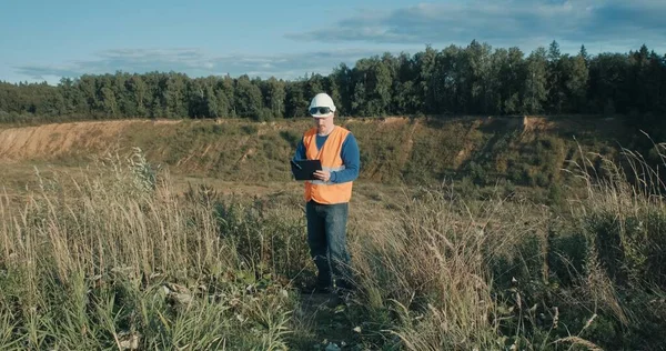 Ingegnere di lavoro in casco accanto alla fossa di sabbia. L'uomo indossa occhiali di saldatura — Foto Stock