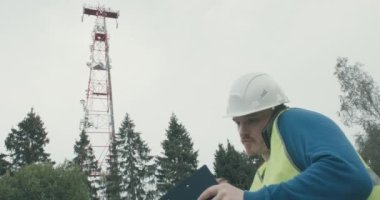 4G ve 5G hücresel radyo kulesi, yanında bir ekolojist duruyor.