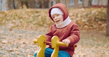 Küçük, sevimli çocuk bahçede salıncakta sallanıyor.