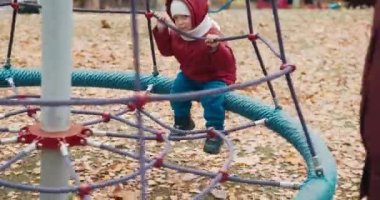 Küçük, sevimli bir çocuk bahçede salıncakta ailesiyle yürüyor.