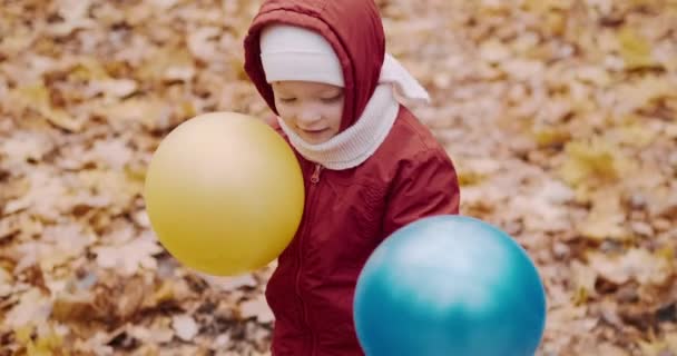 Le petit enfant joue avec sa mère dans des ballons gonflables. Automne nature — Video