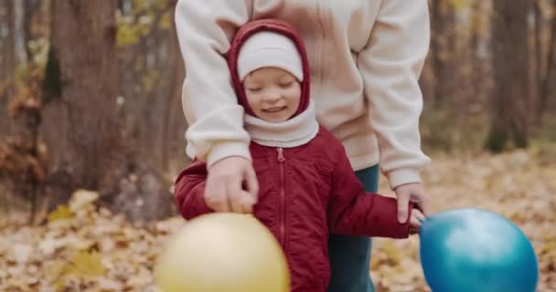 Bambino piccolo sta giocando con sua madre in palloncini gonfiabili. Natura autunnale — Video Stock