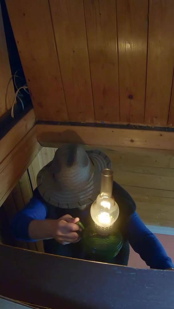 Young man in hat with lamp in his hands goes up to hayloft - Vertical footage — Video Stock