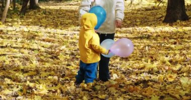 Küçük çocuk annesiyle şişme balonlarla oynuyordu. Sonbahar doğası