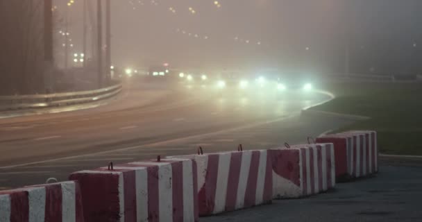 Dusk, fog over highway, cars drive. Part of road is blocked with concrete blocks — Vídeos de Stock