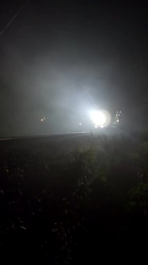 Projektörler gece sisinin içinde parlıyor. Tren işaret veriyor - dikey görüntüler