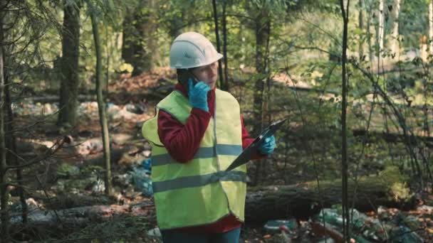 Οικολόγος γυναίκα σε θέματα ενδυμάτων εργασίας πρόστιμο για την απόρριψη πλαστικών αποβλήτων στο πάρκο — Αρχείο Βίντεο