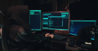 Kaputtaki bir bilgisayar korsanı bilgisayar ekranlarının önünde oturur ve veritabanlarını hackler