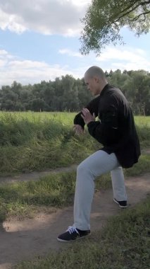 Dövüş sanatlarıyla uğraşan bir adam hayali bir rakibe meydan okuyor - dikey video