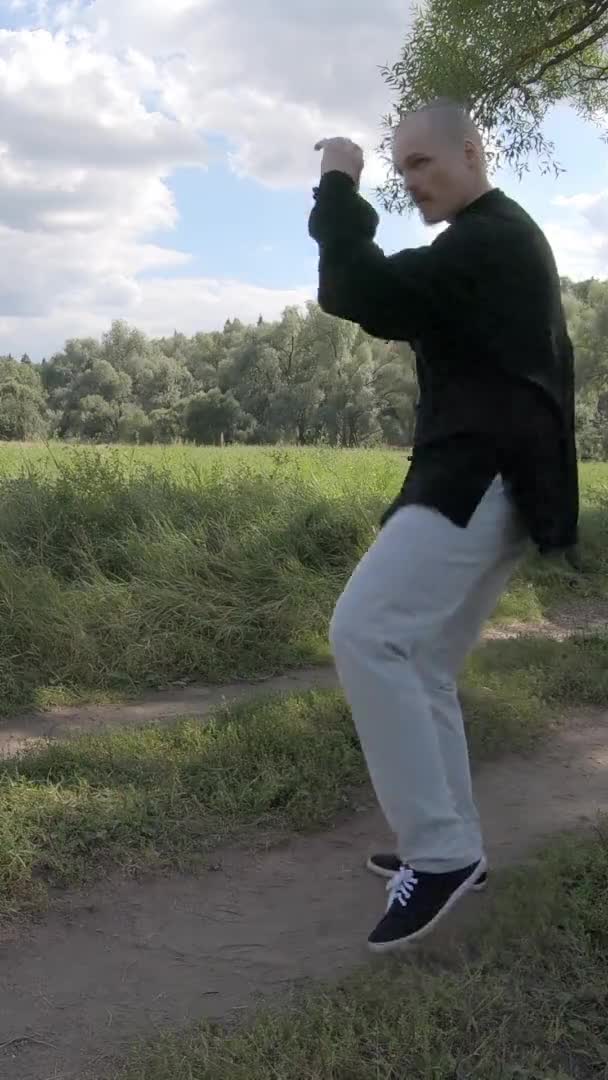 Seorang pria menendang dengan belokan. Terlibat dalam seni bela diri di alam Layar Vertikal — Stok Video