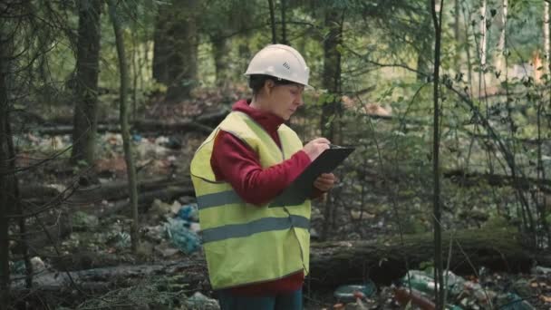 Ecologista mulher em questões de vestuário de trabalho multa por despejar resíduos de plástico no parque — Vídeo de Stock