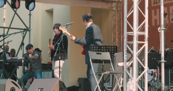 Muzycy rockowi na scenie grają na gitarze elektrycznej i klawiszach. Koncert plenerowy — Wideo stockowe