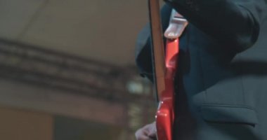 Konserde gitarist bir adam elektro gitar çalar ve dans eder.