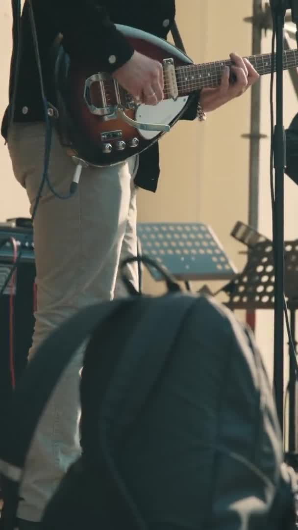 Man gitarist bij een concert speelt een elektrische gitaar en danst. Verticaal scherm — Stockvideo